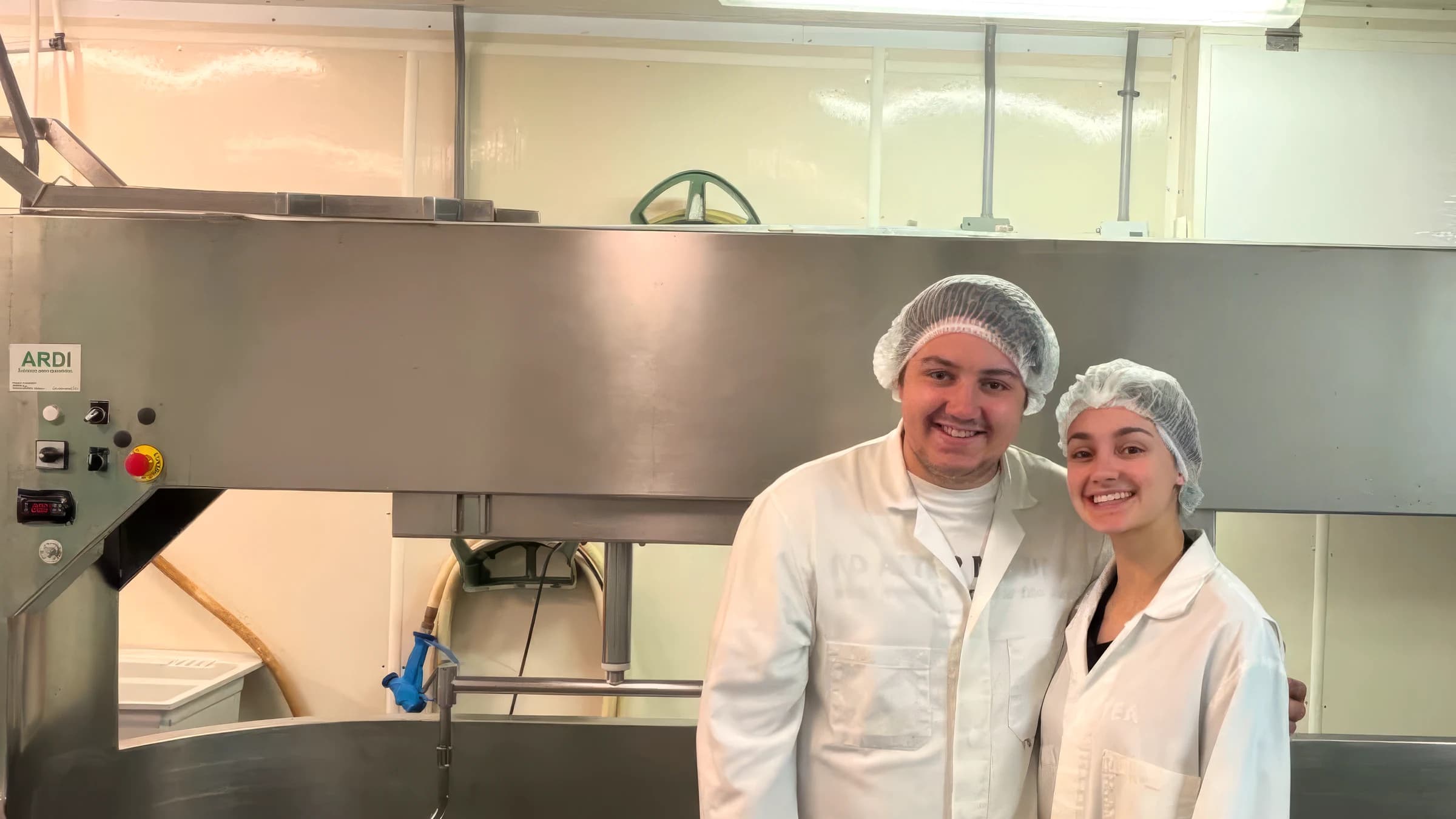 The creamery's owners, in work coats, in front of the production vat